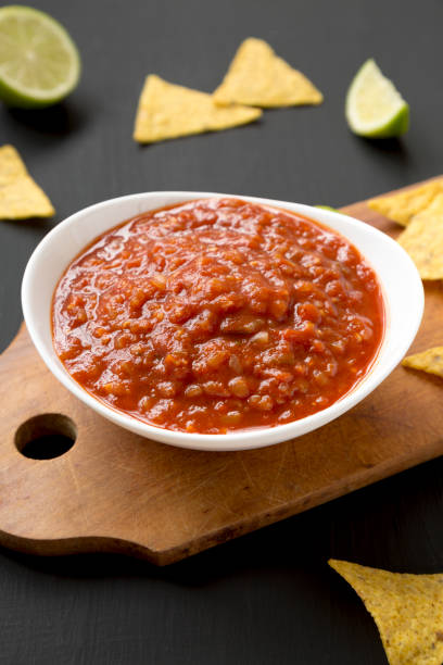 istock Homemade Tomato Salsa and Nachos on a rustic wooden board on a black background, side view. 1331668721