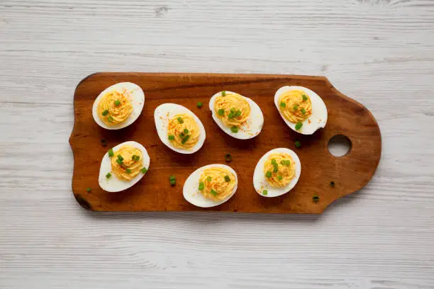 Homemade Deviled Eggs with Chives on a rustic wooden board, top view. Flat lay, overhead, from above.