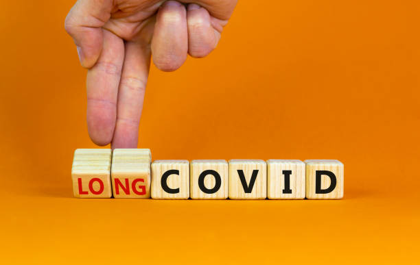 Long covid symbol. Doctor turnes wooden cubes and changes words 'covid' to 'long covid'. Beautiful orange background, copy space. Medical, covid-19 pandemic long covid concept. Long covid symbol. Doctor turnes wooden cubes and changes words 'covid' to 'long covid'. Beautiful orange background, copy space. Medical, covid-19 pandemic long covid concept. long covid stock pictures, royalty-free photos & images