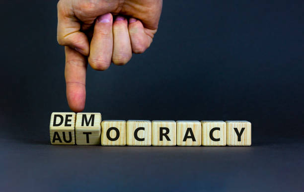 Democracy or autocracy symbol. Businessman turns wooden cubes and changes the word autocracy to democracy. Beautiful grey background, copy space. Business and democracy or autocracy concept. Democracy or autocracy symbol. Businessman turns wooden cubes and changes the word autocracy to democracy. Beautiful grey background, copy space. Business and democracy or autocracy concept. dictator photos stock pictures, royalty-free photos & images