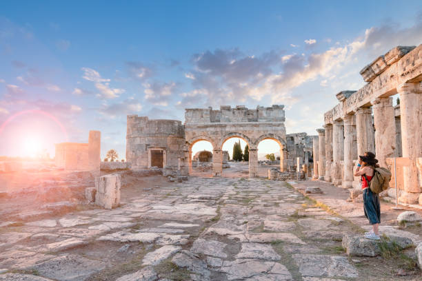 photographe fille touristique prend des photos de la porte frontinus dans les ruines antiques à hiérapolis, pamukkale - hierapolis photos et images de collection