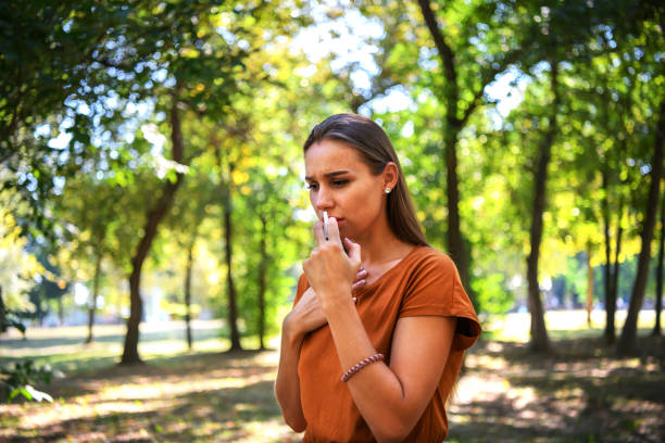 istock A Beautiful Woman is Using Nasal Spray in Public Park. 1331685772