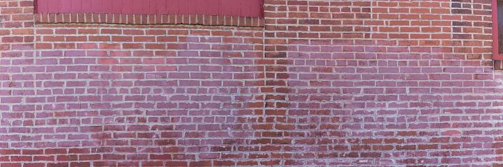Panorama of a red brick wall with painted sections, interesting patina creative copy space, horizontal aspect