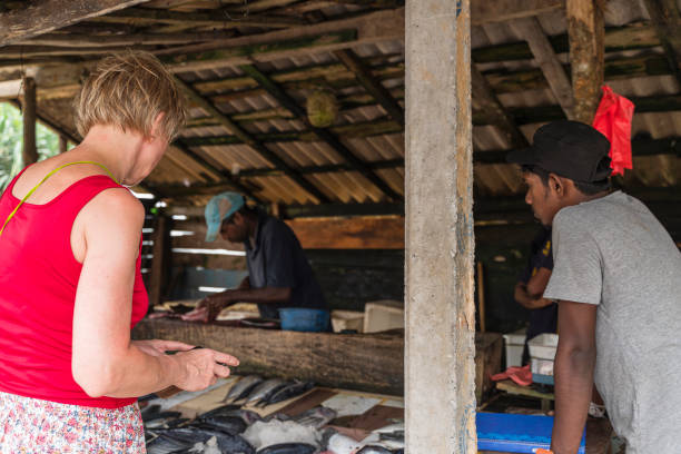 una donna caucasica matura di 55 anni utilizza uno smartphone per scattare foto del pescato fresco in un mercato ittico locale in sri lanka. - women mature adult 50 55 years 50s foto e immagini stock