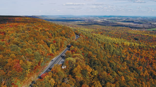 Remote scenic aerial view on the highway in the Appalachian Mountains with the remote Lehigh Valley, Poconos, Pennsylvania, in the backdrop on the autumn evening. Aerial video with the forward camera motion.