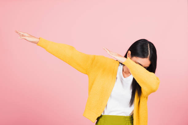 woman teen smile standing move showing DAB dance against gesture Asian happy portrait beautiful cute young woman teen smile standing move showing DAB dance against gesture raise hands arms covering  face isolated, studio shot on pink background with copy space dab dance stock pictures, royalty-free photos & images