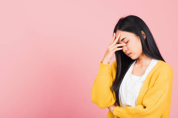 woman sad tired strain face holding hold head by hands Portrait of beautiful Asian young woman sad tired strain face holding hold head by hands, female person closed eyes problem she headache, studio shot isolated on pink background anemia photos stock pictures, royalty-free photos & images