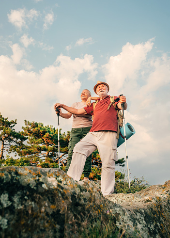 Photo of an elderly couple during their hike with backpacks, reached the top of the mountain