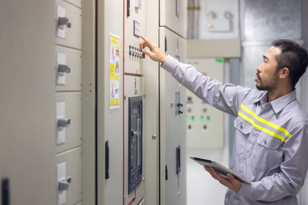 engenheiro ou técnico usando tablet para monitorar o conceito de processo, negócios e indústria em sala elétrica de engrenagem de switch de plataforma de óleo e gás ou planta industrial. - electricity control panel engineer electronics industry - fotografias e filmes do acervo