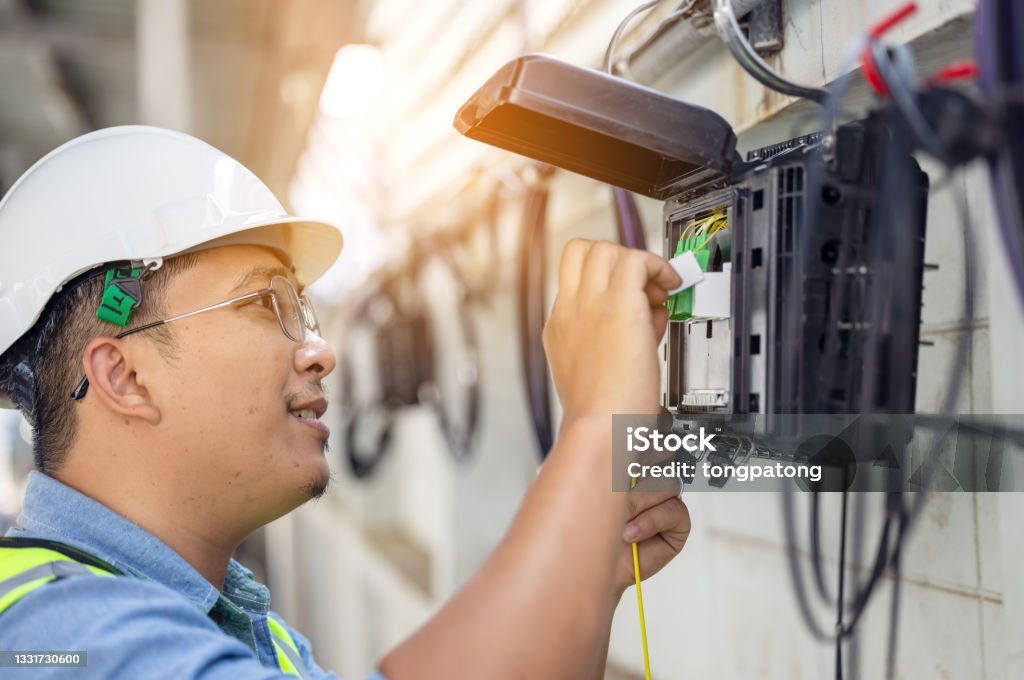 An internet technician is repairing or maintaining a fiber optic connection by opening a fiber optic connector. Fiber Optic Stock Photo