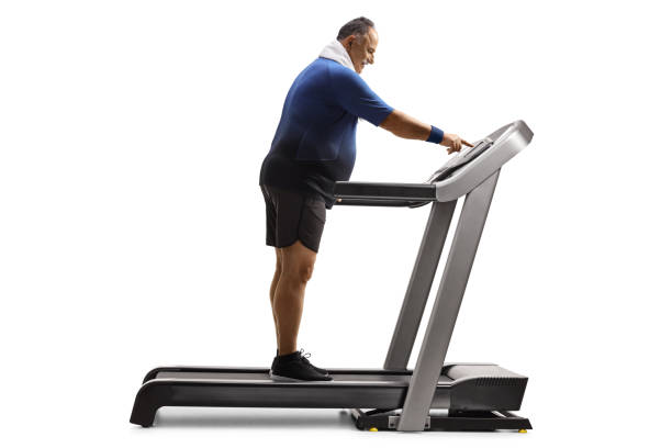 istock Mature man pushing a power switch on a treadmill isolated on white background 1331738951