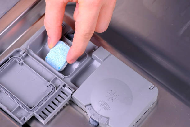 istock Man's hand is putting detergent tablet in automatic compartment in dishwasher. 1331741024