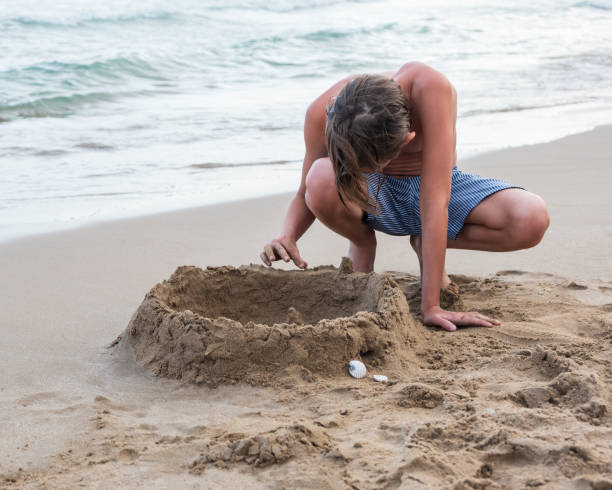 istock Boy on the beach plays with sand 1331750752