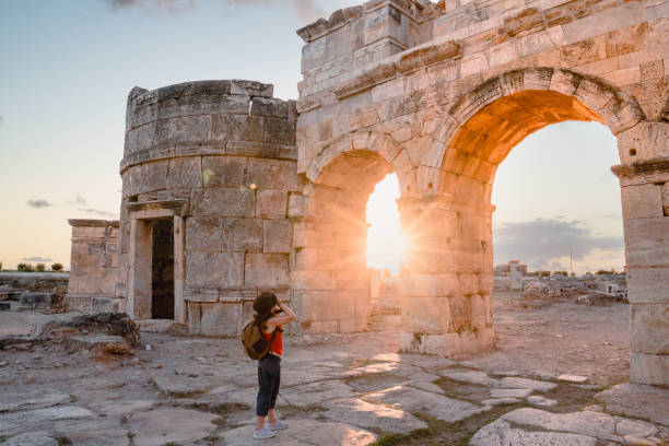 photographe fille touristique prend des photos de la porte frontinus dans les ruines antiques à hiérapolis, pamukkale - hierapolis photos et images de collection