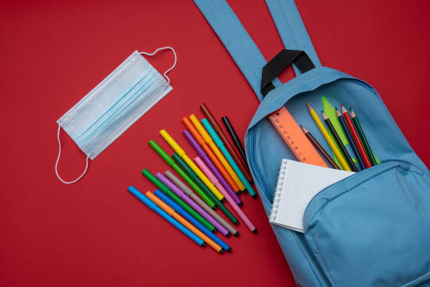 istock COVID-19 prevention while going back to school and new normal concept.Top view of backpack with school supplies mask and on red background. 1331754901