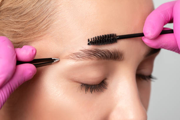 istock Makeup artist combs  and plucks eyebrows after dyeing in a beauty salon.Professional makeup and cosmetology skin care. 1331755122