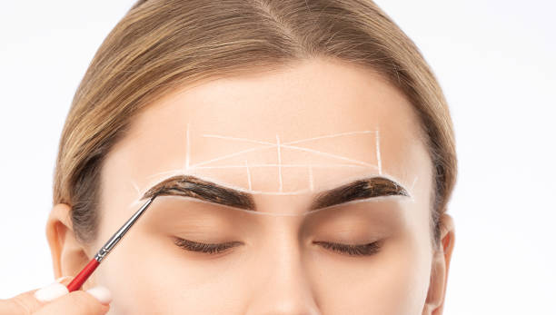 istock Make-up artist makes markings with white pencil for eyebrow and paints eyebrows. Professional makeup and facial care. 1331755379