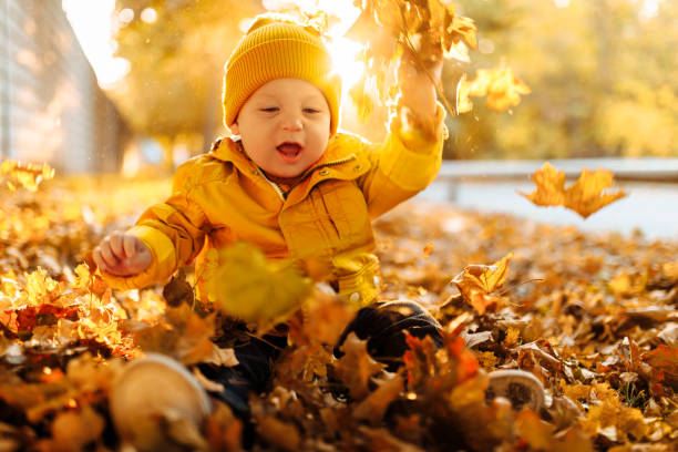 istock happy boy playing with fallen leaves in autumn park 1331757834