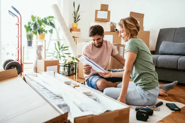 Couple moving in new apartment and assembling furniture