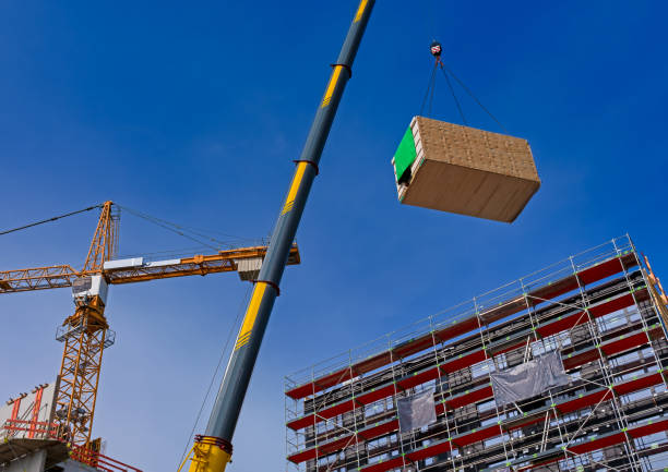 Crane lifting heavy load material on a construction site with blue sky background