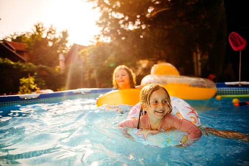 Children in bathing suits play in pool in the summer.