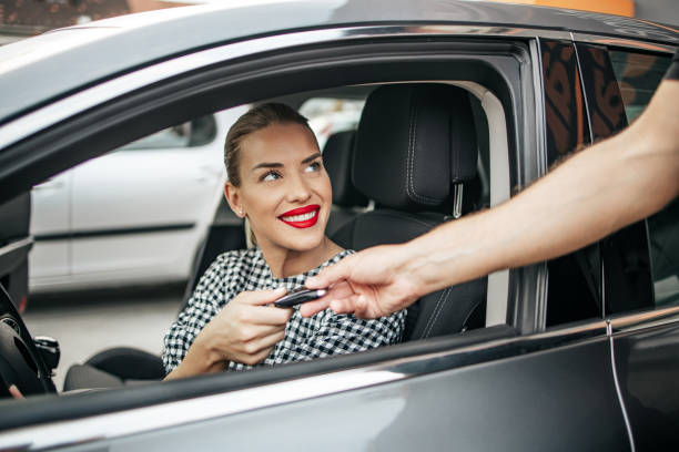 propietario de coche nuevo sentado en el coche y tomar las llaves del vendedor - alquiler de coche fotografías e imágenes de stock