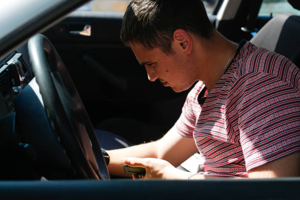 istock Serious successful caucasian young man sitting in car. 20s guy looking down from window. Silver grey gray car. Attractive brunette men in vehicle. Buyer or auto dealer concept. First owner 1331773739
