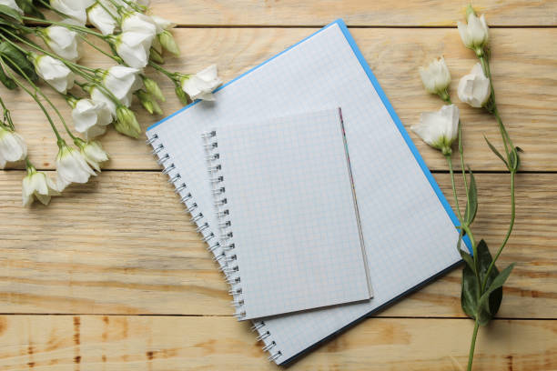 istock Notebook with a pencil and white flowers on a natural wooden table. top view 1331775558