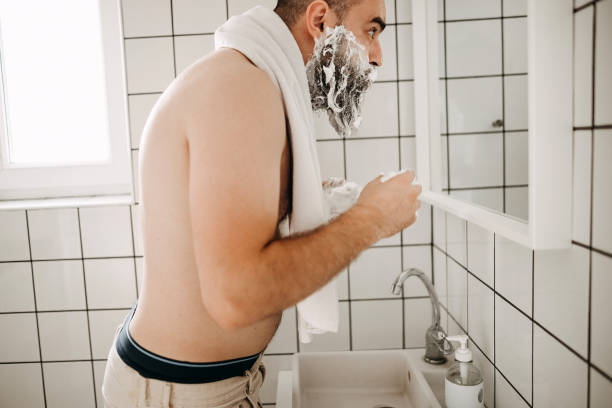 istock Happy man applying shaving foam at bathroom mirror 1331777608
