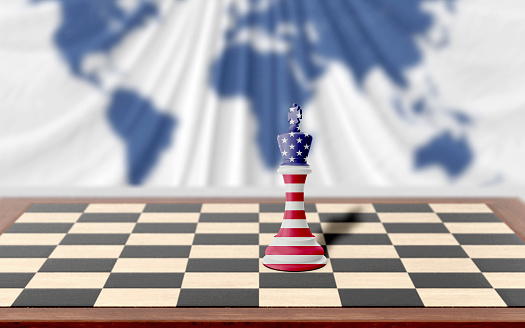 American chess king covered with country flag is on a wooden chess board on table against world map background. Easy to crop for all your social media and design need with copy space.