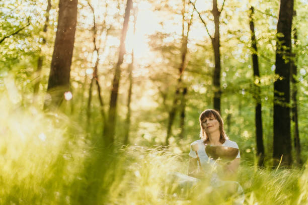 istock Woman sitting and using a rin gong in the forest 1331778898