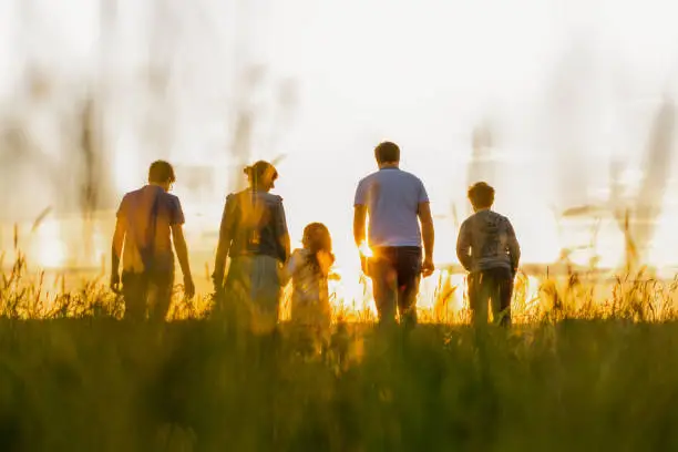 Photo of Family with three children walking on grass field