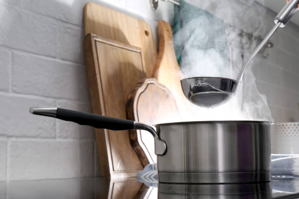 istock Adding water with ladle into steaming saucepan on stove in kitchen 1331782565