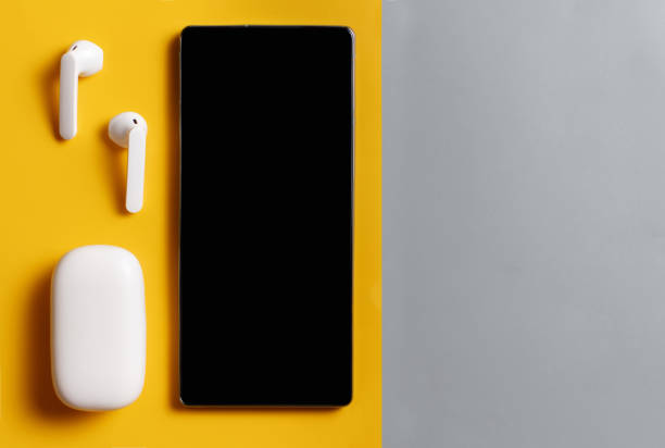 istock Smartphone and white wireless earphones with the case on grey and yellow background 1331783921