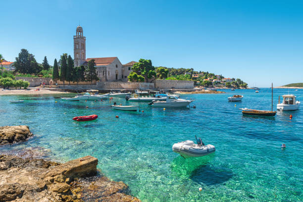 turkusowa woda zatoki adriatyckiej na wyspie hvar z klasztorem franciszkanów i łodziami w regionie dalmacji, chorwacja - croatia zdjęcia i obrazy z banku zdjęć