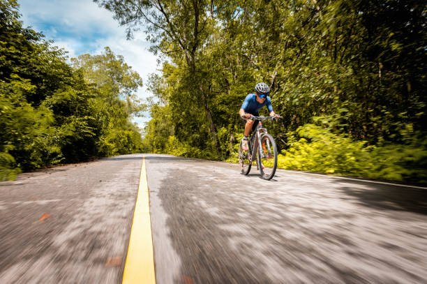 istock Cyclist speeding mountain bike on road with forest side. 1331785748