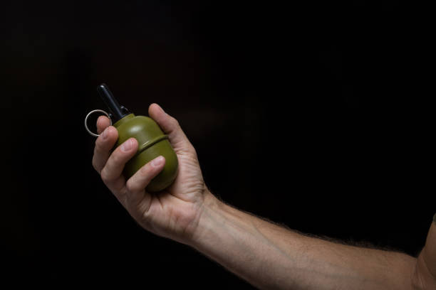 Grenade in flight with safety pin. A soldier in a mask threw a grenade, top view, focus on the grenade. open-wheel single-seater car grenade in flight.