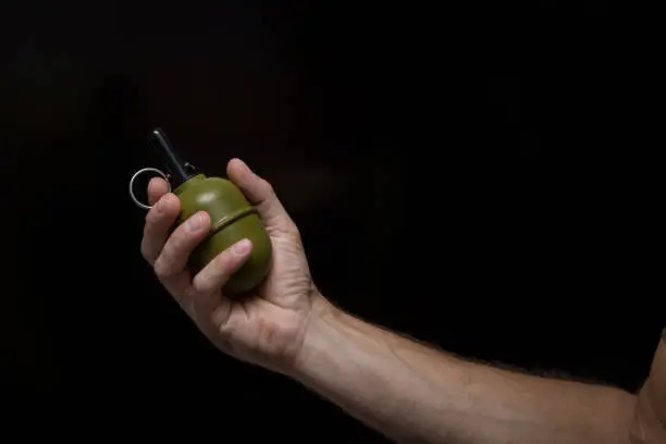 anti-personnel grenade in hand, black background, strike ball, hand grenade, military theme