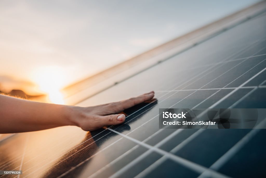 Human hand touching solar panel Close-up of human hand touching solar panel during Sunset Solar Panel Stock Photo