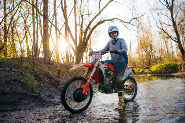 istock Motocross rider riding through stream in forest 1331796737