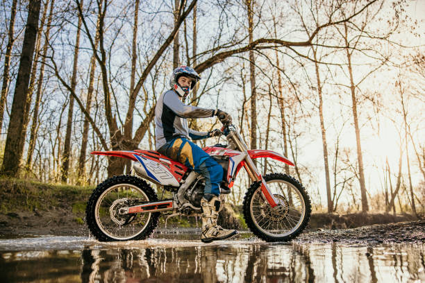 istock Motocross rider riding through stream in forest 1331796936