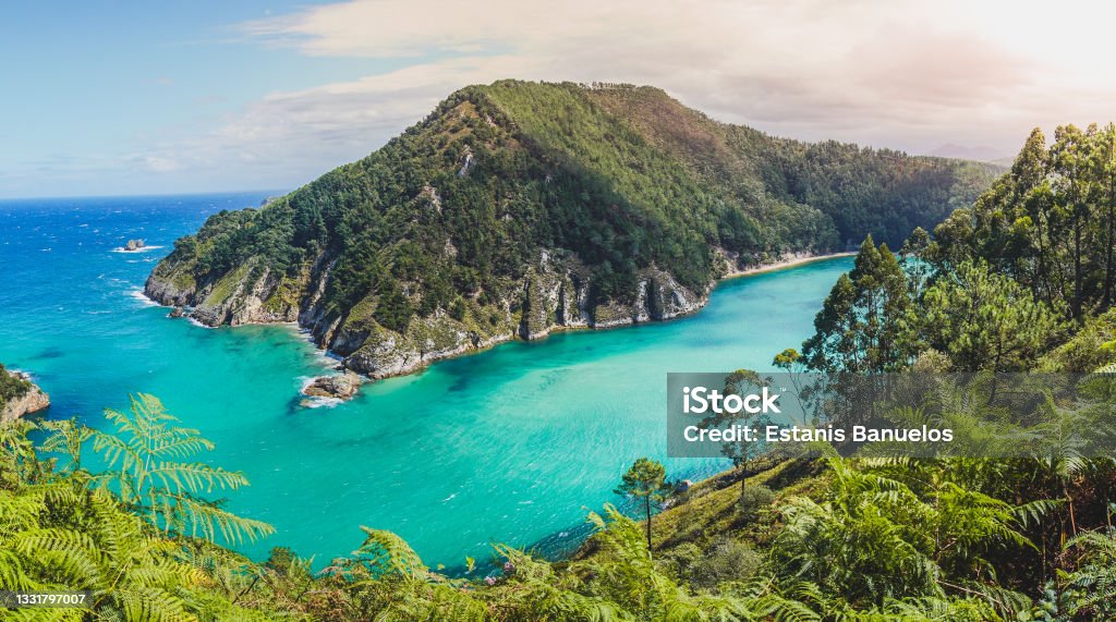 Panoramic of the bay of Pechón in Cantabria Spain. Turquoise waters of white sand on a sunny day. Small waves. Cantabria Stock Photo