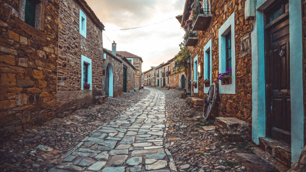 одинокая старая мощеная прогулка между домами в городке под названием кастрильо-де-лос-полвазарес, в леоне, на солнечном закате. - castile and leon стоковые фото и изображения