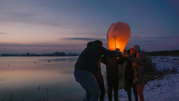 family examining burning sky lantern - balloon child winter snow imagens e fotografias de stock