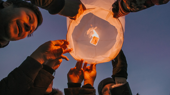 Family in warm clothing about to release burning sky lantern