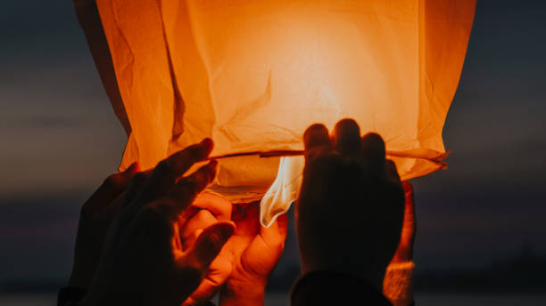 manos que sueltan la linterna del cielo en llamas - chinese lantern fotografías e imágenes de stock