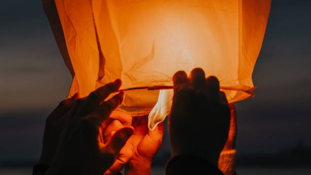 mani che rilasciano lanterna del cielo in fiamme - chinese lantern foto e immagini stock