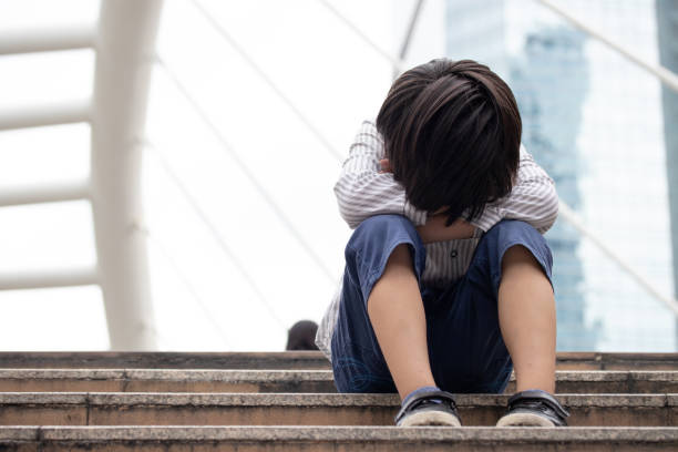 niño asiático sin hogar sentado solo en la escalera en la calle. pobre, triste, asustado y solo. - little boys child sadness depression fotografías e imágenes de stock