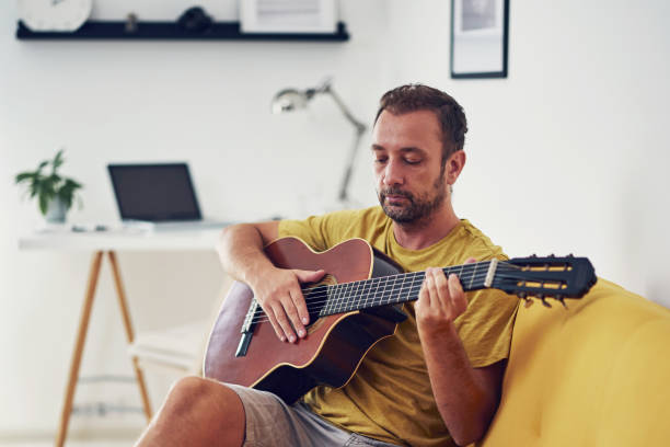 istock Man playing acoustic guitar at home. 1331799762