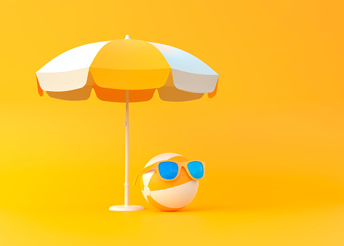 Pelota de playa bajo sombrilla con gafas de sol sobre fondo amarillo photo